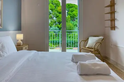 a bedroom with a white bed and a window at Zen Vouliagmeni Beach Apartment 2 in Athens