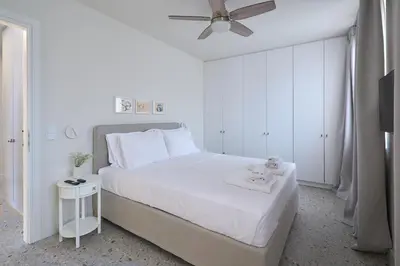 a white bedroom with a bed and a ceiling fan at Penthouse in the heart of Athens in Athens