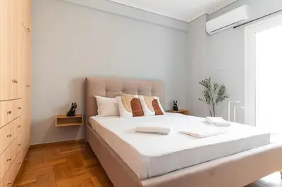 a white bedroom with a large bed with white sheets at Elegant 3 Bdr Apartment City Retreat in Kypseli in Mesochórion