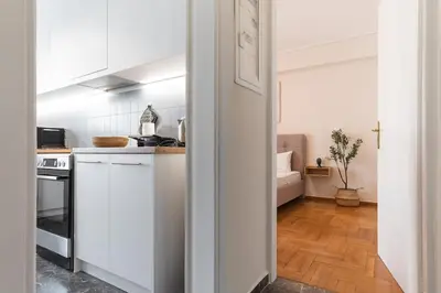 a kitchen with white cabinets and a wooden floor at Elegant 3 Bdr Apartment City Retreat in Kypseli in Mesochórion