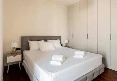 a white bedroom with a large white bed with two pillows at Stylish 2-Lvl maisonette near to Acropolis Museum in Athens