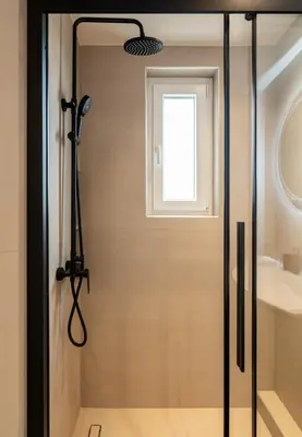 a glass shower door in a bathroom with a window at Stylish 2-Lvl maisonette near to Acropolis Museum in Athens