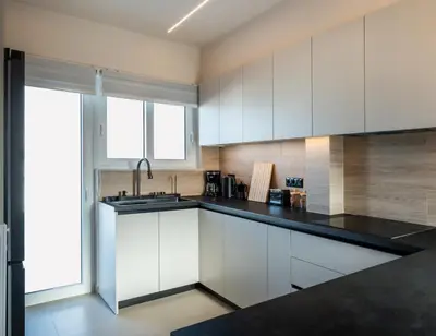a kitchen with white cabinets and a black counter top at Stylish 2-Lvl maisonette near to Acropolis Museum in Athens