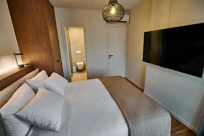 a bedroom with a white bed with a flat screen tv at By the Ellinikon in Athens
