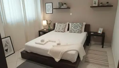 a bedroom with a large bed with white sheets and pillows at The Calm Corner of Ampelokipoi in Athens