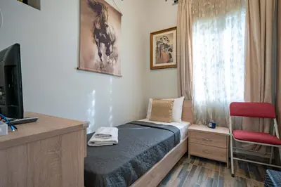 a small bedroom with a bed and a television at Attiki Haven - 4BR Stay - Steps from Metro by ΜΡS in Athens