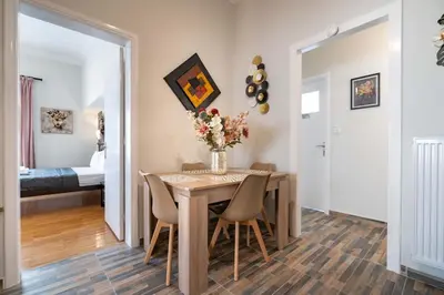 a dining room with a table with chairs and a vase of flowers at Attiki Haven - 4BR Stay - Steps from Metro by ΜΡS in Athens