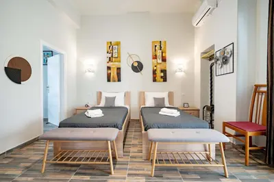 a room with two beds and a table and chairs at Attiki Haven - 4BR Stay - Steps from Metro by ΜΡS in Athens