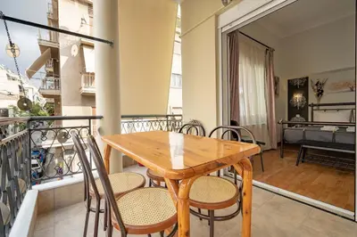 a wooden table and chairs on a balcony at Attiki Haven - 4BR Stay - Steps from Metro by ΜΡS in Athens