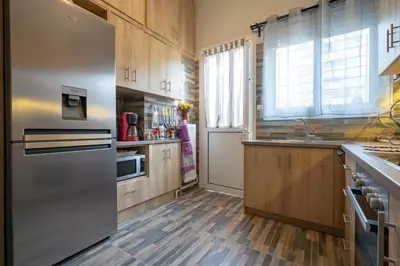 a kitchen with a stainless steel refrigerator and wooden cabinets at Attiki Haven - 4BR Stay - Steps from Metro by ΜΡS in Athens