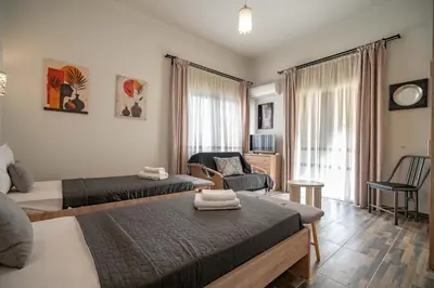 a bedroom with two beds and a living room at Attiki Haven - 4BR Stay - Steps from Metro by ΜΡS in Athens