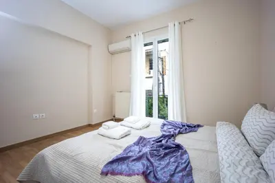 a white bedroom with a bed with towels on it at Modern City Retreat in Kallithea in Athens
