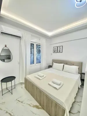 a white bedroom with a large bed with two towels on it at Cozy 30sqm Studio in the Heart of Athens in Athens