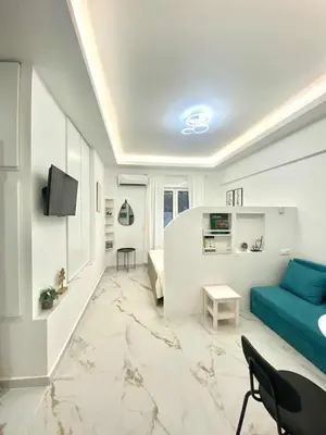 a living room with a blue couch and a tv at Cozy 30sqm Studio in the Heart of Athens in Athens
