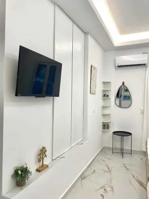 a living room with a tv on a white wall at Cozy 30sqm Studio in the Heart of Athens in Athens