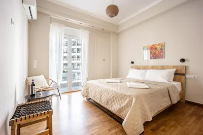 a white bedroom with a large bed and a chair at Athens #1 Experience in Athens