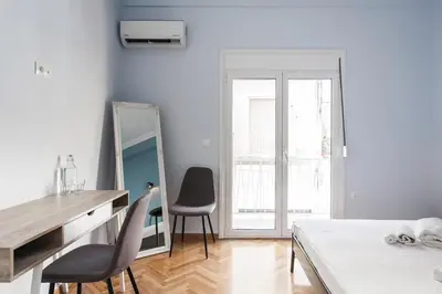 a bedroom with a bed and two chairs and a mirror at Spacious 3br Apartment with Terrace in Exarchea in Athens