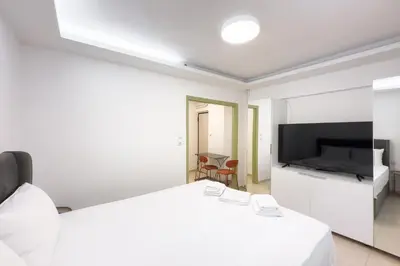 a white bedroom with a bed and a flat screen tv at Central Nest near Acropolis in Athens