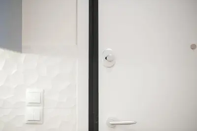 a glass shower door with a white wall at Panormou Neon - Urban Apartment 3A in Athens