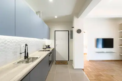 a white kitchen with a sink and a tv at Panormou Neon - Urban Apartment 3A in Athens