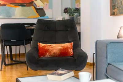 a black chair with a orange pillow in a living room at Stylish Flat between Syntagma Sq and Kolonaki in Athens