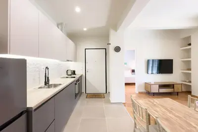 a kitchen with white cabinets and a wooden table at Panormou Neon - Urban Apartment 4A in Athens