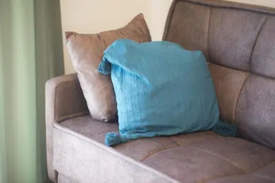 a blue pillow sitting on a brown couch at Panormou Neon - Urban Apartment 4A in Athens