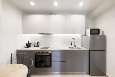 a white kitchen with a sink and a refrigerator at Panormou Neon - Urban Apartment 4B in Athens