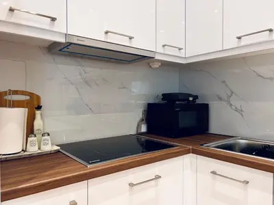 a kitchen with white cabinets and a black microwave at Hodos Luxury APT 2 near ATH-Airport in Markopoulo