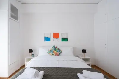 a white bedroom with a bed and two lamps at Cozy Apartment in Athens with Balcony, 5 min to Metro in Athens