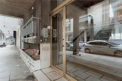 a store front with a reflection of a car in a window at 15 mins Walk to Acropolis, Minimalist Studio in Athens