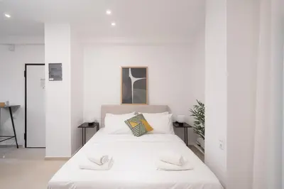 a white bedroom with a large bed with white sheets at 15 mins Walk to Acropolis, Minimalist Studio in Athens