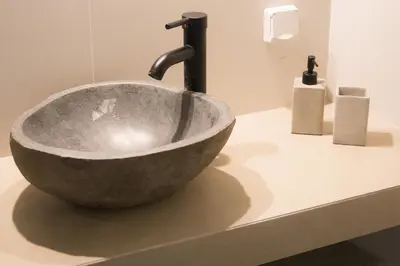 a bathroom sink with a large stone bowl at Panormou Neon - Urban Apartment 1A in Athens