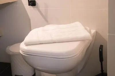 a white toilet with two towels on top of it at Panormou Neon - Urban Apartment 1A in Athens