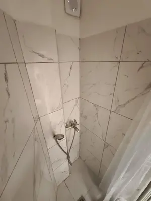 a bathroom with a shower with white marble walls at Beehive Mini Rooms in Athens