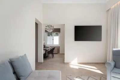 a living room with a couch and a tv on a wall at Elaia House Glyfada in Athens