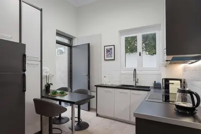 a kitchen with white cabinets and a black counter top at Elaia House Glyfada in Athens