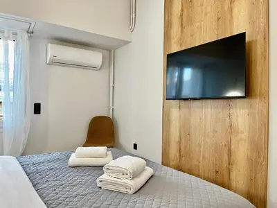 a bedroom with a bed with a flat screen tv on the wall at New Sleek apartment in the center of AThens in Athens