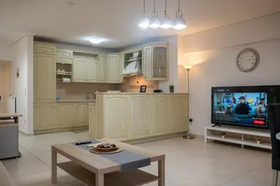 a kitchen with white cabinets and a tv and a table at Spacious 2BR, hot tub, prvt parking, near metro in Athens