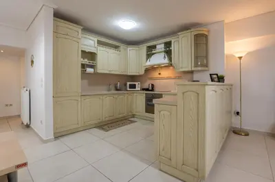 a kitchen with wooden cabinets and a tile floor at Spacious 2BR, hot tub, prvt parking, near metro in Athens