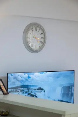 a clock hanging on a wall above a tv at Spacious 2BR, hot tub, prvt parking, near metro in Athens