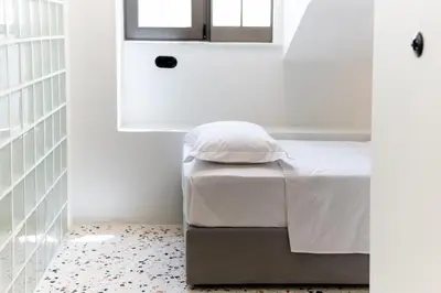 a bedroom with a bed with white sheets and a window at Glass Nest Athens 2BR Apartment near Metro & Airport Line in Athens