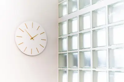 a clock on a wall next to a window at Glass Nest Athens 2BR Apartment near Metro & Airport Line in Athens