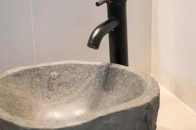 a stone sink with a faucet in a bathroom at Panormou Neon - Urban Apartment 1B in Athens