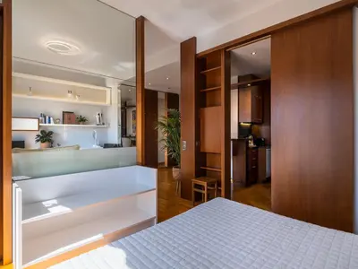 a bedroom with a white bed and a kitchen at Phos, an eclectic suite with stunning Acropolis view in Athens