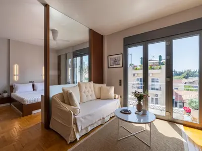a living room with a couch and a bed and a table at Phos, an eclectic suite with stunning Acropolis view in Athens