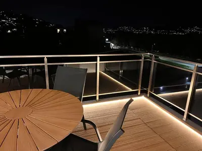 a wooden table and chair with an umbrella on a balcony at Amelia luxury beachfront apartment near airport in Porto Rafti