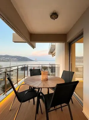 a table and chairs on the balcony of a house at Amelia luxury beachfront apartment near airport in Porto Rafti