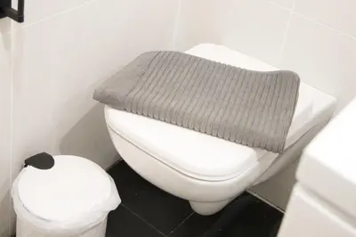 a white toilet with a gray blanket on top of it at Panormou Neon - Urban Apartment 2B in Athens