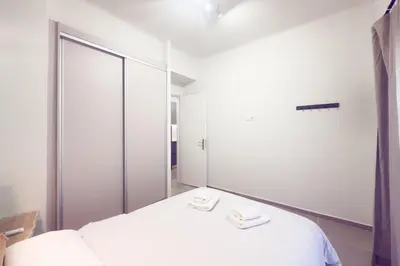 a bedroom with a white bed with a large mirror at Panormou Neon - Urban Apartment 2A in Athens
